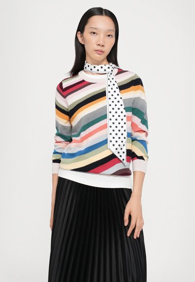 Maglione a strisce multicolori con maniche lunghe e sciarpa a pois bianchi; abbinato a una gonna nera plissettata, creando un look stratificato.