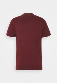 T-shirt di cotone bordeaux con maniche corte, scollo tondo e texture liscia; design semplice senza motivi o accenti visibili.