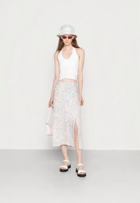 Top cropped branco, saia midi com padrão pastel e fenda lateral, sandálias brancas, chapéu bucket pastel e bolsa rosa.