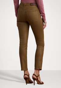 Bruna, kroppsnära jeans med bakfickor, tillverkade av denim, med en slät yta, midjehöjd och parades med bruna klackar.