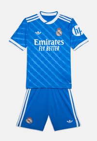 Modrý futbalový dres s pruhovaným tričkom a bielymi doplnkami, brandingom "Emirates" a zodpovedajúcimi šortkami s detailmi loga.