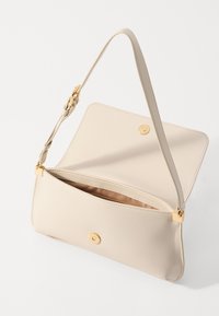 Beige leather bag with a smooth texture, a single shoulder strap, a magnetic closure, and a single interior compartment.