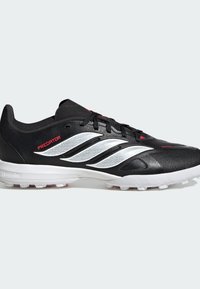 Μαύρο και άσπρο ποδοσφαιρικό παπούτσι Adidas Predator με κορδόνια και υφασμένη σόλα, με τρεις λευκές ρίγες και κόκκινες λεπτομέρειες με το λογότυπο.