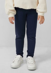 Marineblauwe katoenen leggings met een snug fit, gecombineerd met witte sneakers met veters en zijritsen. Zachte textuur, minimalistisch ontwerp.