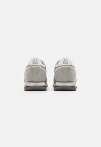 Scarpe sportive grigie con una parte superiore in suede e mesh, colletto imbottito e dettaglio del logo. Presentano una suola in gomma testurizzata per una buona aderenza.
