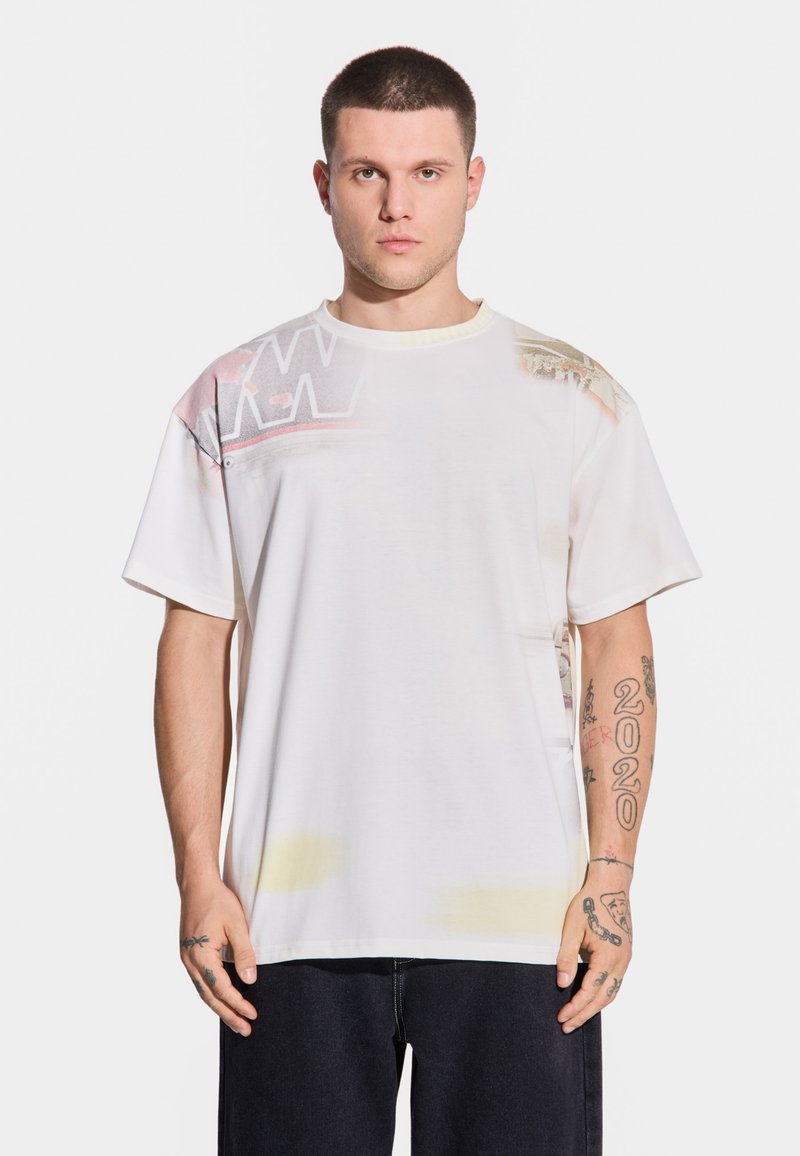 Biała bawełniana koszulka z okrągłym dekoltem, krótkimi rękawami oraz graficznymi wzorami w pastelowych kolorach na jednym ramieniu i górnej części klatki piersiowej.