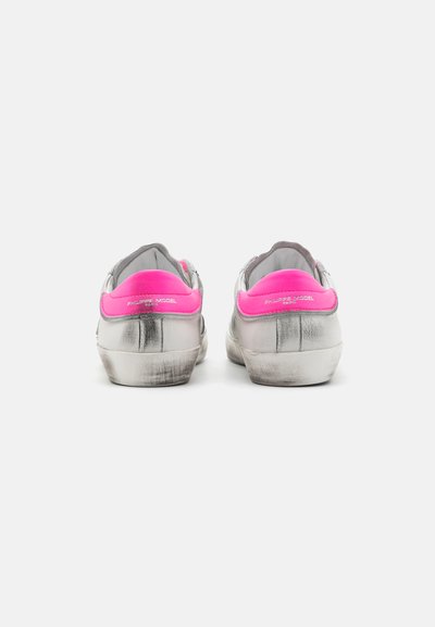Silver sneakers with pink heel accents, smooth texture, minimalistic design, and branding on the back. Note scuff marks on the soles.