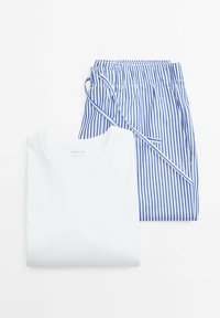 T-shirt bianco in cotone con colletto rotondo, abbinata a pantaloni con lacci blu e bianchi a righe, entrambi stesi su uno sfondo chiaro.