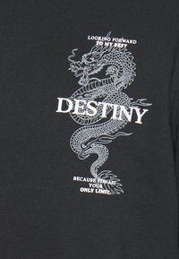 T-shirt in cotone nero con una grafica di un drago bianco e la scritta "DESTINO" con frasi motivazionali aggiuntive sotto.