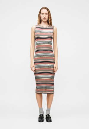 Woman wearing a sleeveless, mid-calf knit dress with horizontal multicolor stripes, gray socks, and black loafers, standing against a plain background.