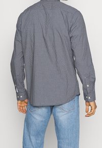 Herrskjorta med lång ärm i marinblått och vitt rutmönster, knappkrage och justerbara manschetter. Bomullstyg med en mjuk textur.