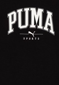 Camiseta negra con un gran texto blanco "PUMA" y una etiqueta más pequeña "SPORTS" debajo, con un pequeño logo de puma saltando en blanco.