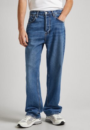 Blå denim jeans med lige ben, fem lommer og kontrasterende syninger. Bæret med hvide sneakers, der fremhæver det afslappede fit.