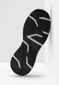 Suola in gomma nera con motivi e scanalature testurizzati; presenta dettagli bianchi; mostra un design complessivo di scarpa atletica resistente.