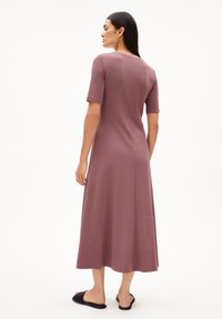 Mauve, knee-length dress with short sleeves and a fitted waist, made from textured fabric. Paired with black slide sandals.