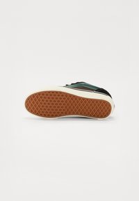 Bota s černým svrškem, tyrkysovými akcenty a texturovanou gumovou podrážkou se vzorem diamantů pro lepší grip.