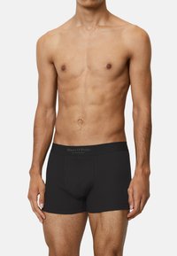Schwarze Boxershorts mit taillierter Passform, aus glattem Stoff gefertigt. Verfügt über einen weichen, elastischen Bund mit dem Markennamen darauf gedruckt.