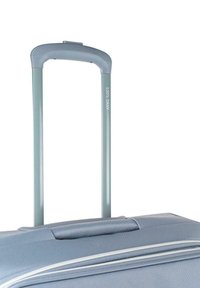 Maleta de concha dura con un exterior de color azul claro, un mango telescópico y una superficie texturizada con costuras blancas de acento.