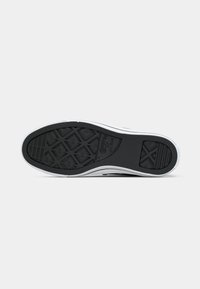 Talpa de sneaker din cauciuc negru cu un model texturat de aderență, având zone întărite și detalii laterale albe. Formă rectangulară cu margini curbate.