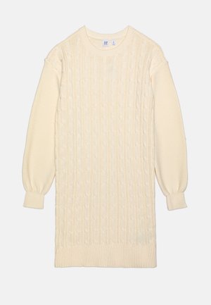 Robe-pull en maille de couleur crème avec manches longues, col rond et motif torsadé sur le devant.