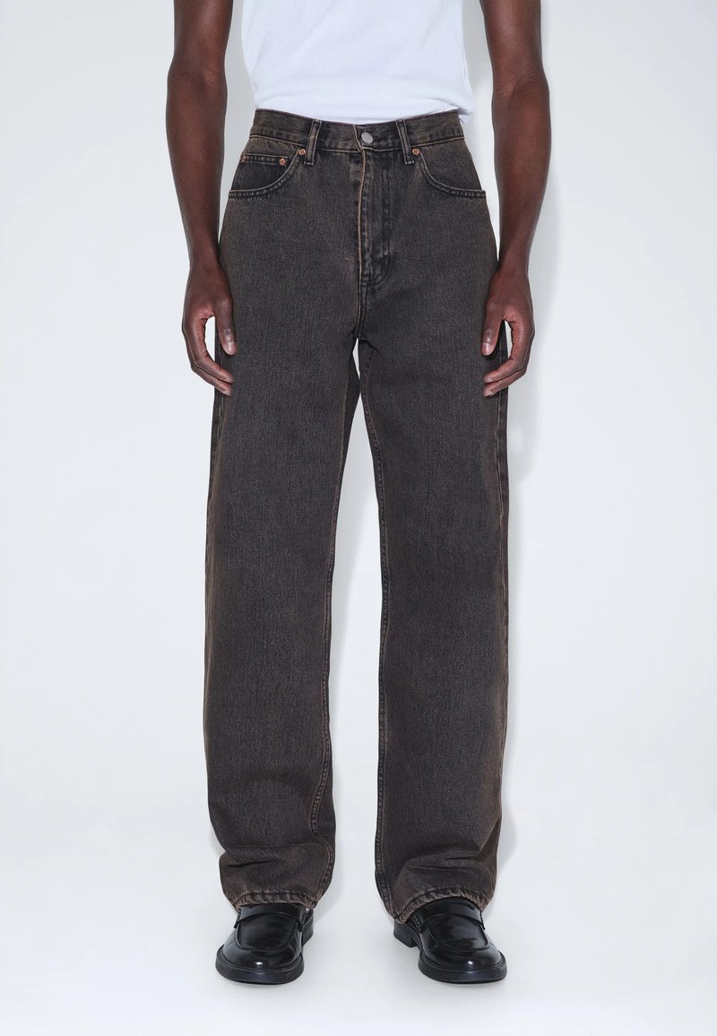 Schwarze Jeans mit weitem Bein, Fünf-Taschen-Design, hoher Bund und dezente Steppdetails. Glatte Textur und minimale Metallakzente.