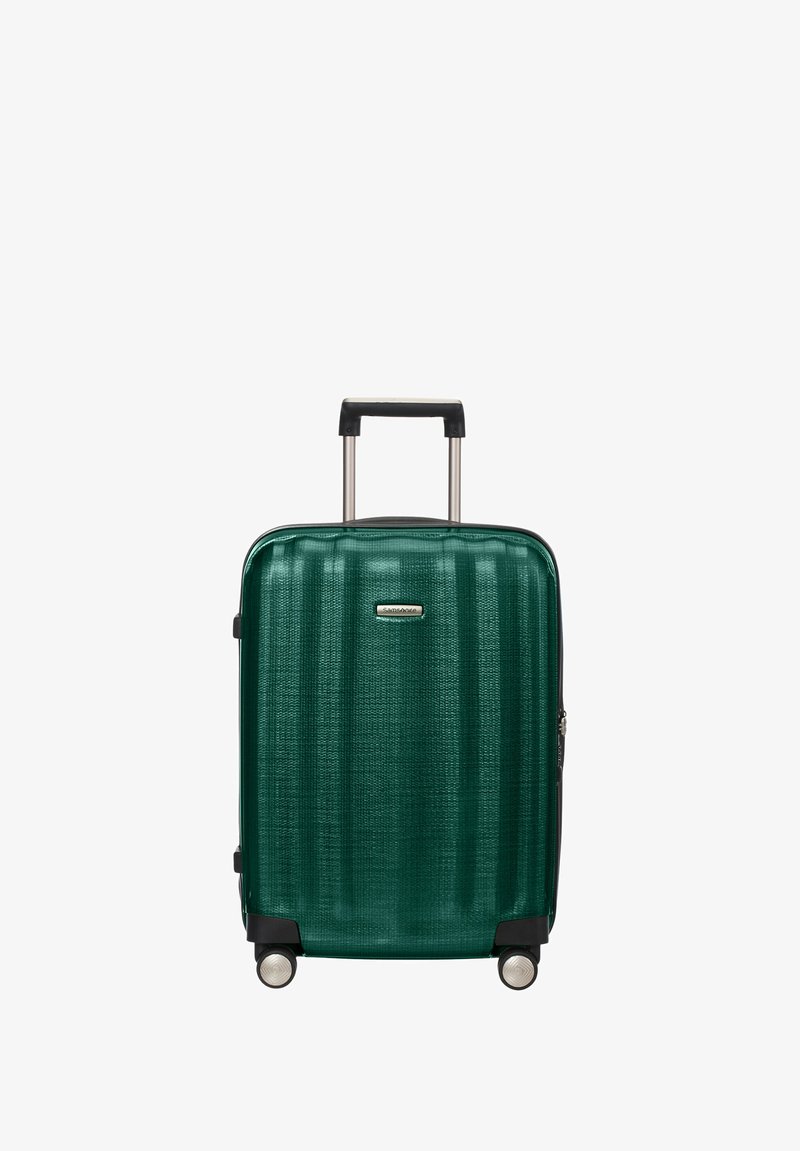 Green hardshell carry-on suitcase with a textured surface, retractable handle, four wheels, and a silver brand logo near the top.