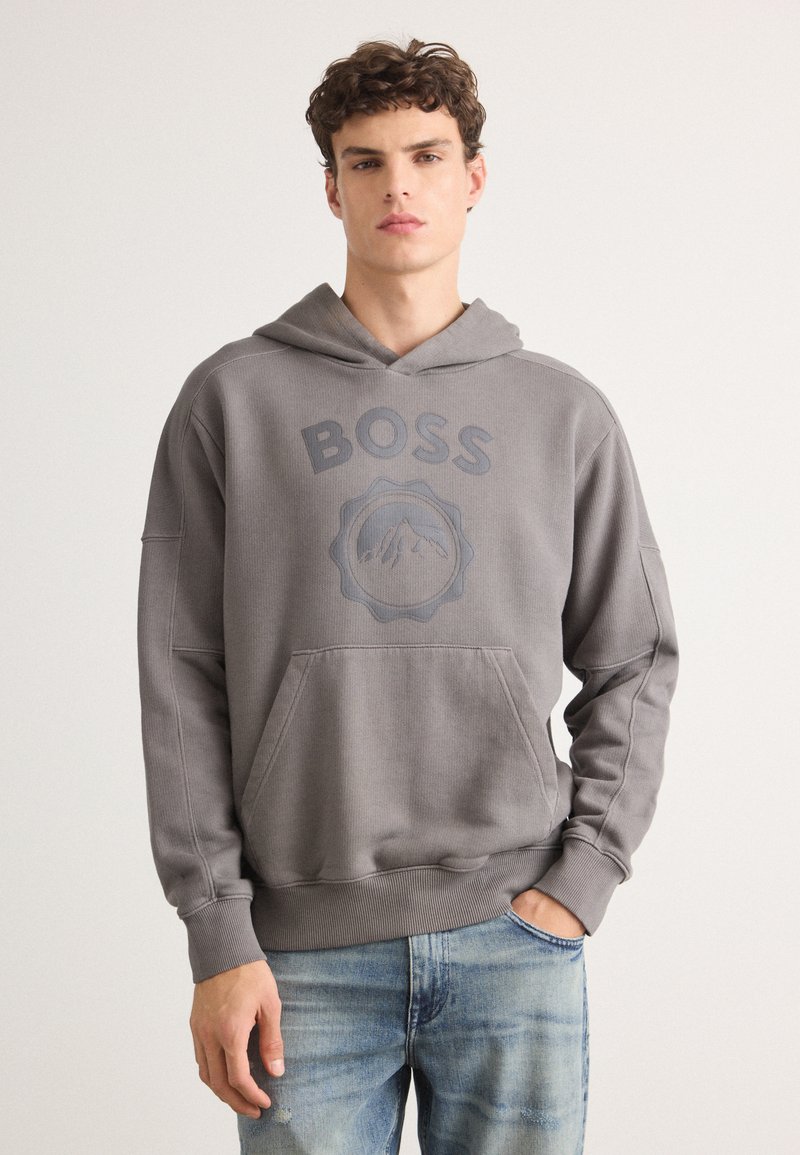 Hanorac gri cu glugă și buzunar în față, cu imprimeu "BOSS" și grafică montană. Textură moale, croială casual, manșete cordonate.