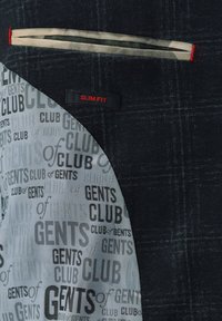 Black slim-fit jacket with textured fabric, featuring a grey lining with repeated text pattern. Red accent on pocket lining.