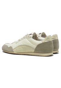 Beige ruskind- og lædersneakers med en tekstureret finish, der har en rund tå, snørebånd foran og en flad gummisål.