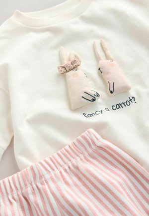 Sweatshirt crème avec deux appliqués de lapin en peluche et du texte brodé ; associé à un short à taille élastique rose et blanc à rayures.