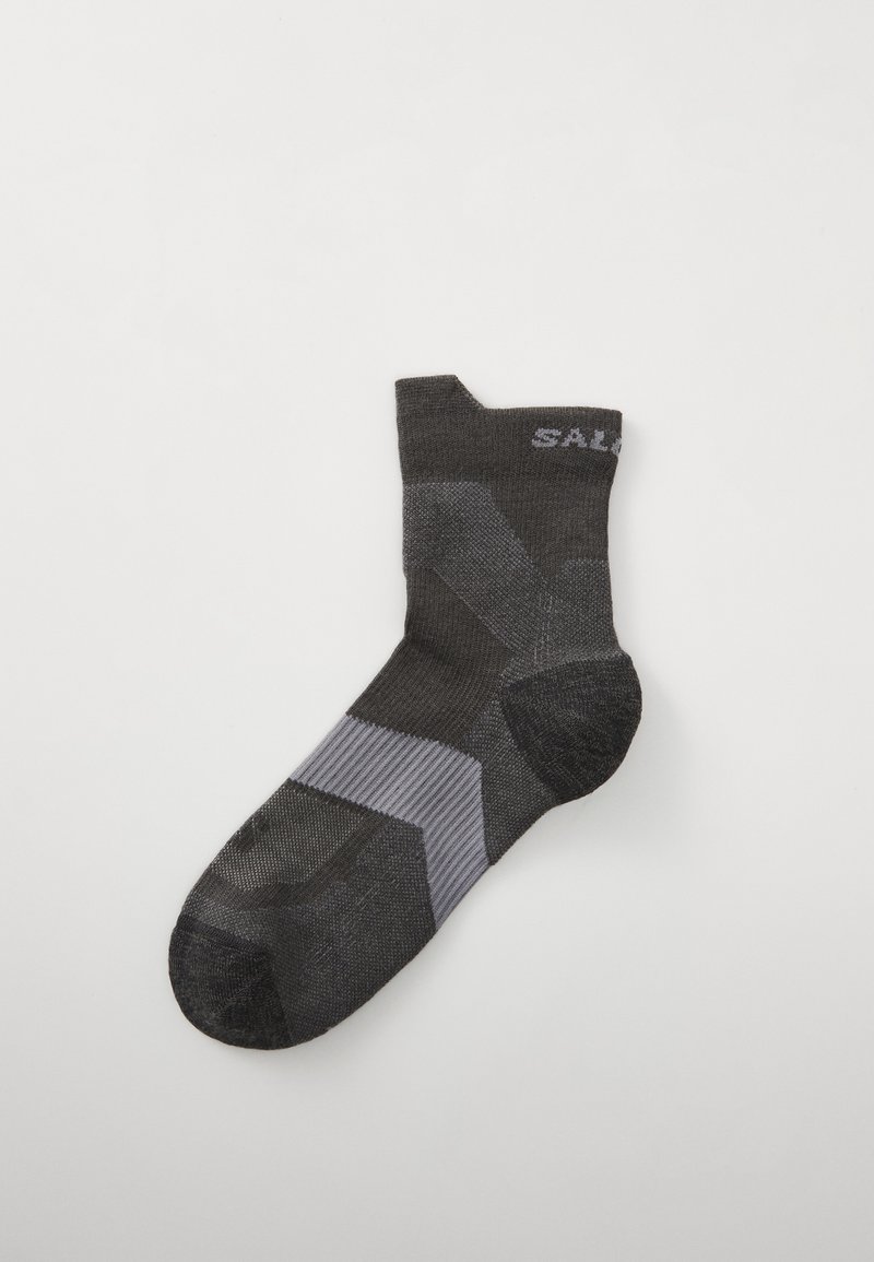 Calcetín deportivo negro con patrón geométrico gris; cuenta con textura acanalada, puntera y talón reforzados, y un diseño de corte bajo.