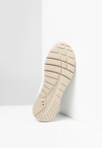 Sole di sneaker beige con texture a grip, che presenta il nome del marchio "NeroGiardini" e una piccola bandiera italiana. Finitura liscia e bordi arrotondati.