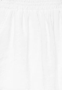 Gonna bianca con vita elasticizzata arricciata, realizzata in un tessuto leggero e morbido. Il design è fluido con drappeggi soffici e una texture minima.