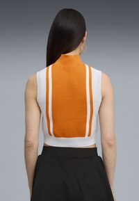 Suéter corto blanco con una parte posterior a rayas naranjas y cuello simulado. Presenta un acabado texturizado con dos rayas blancas en los lados.