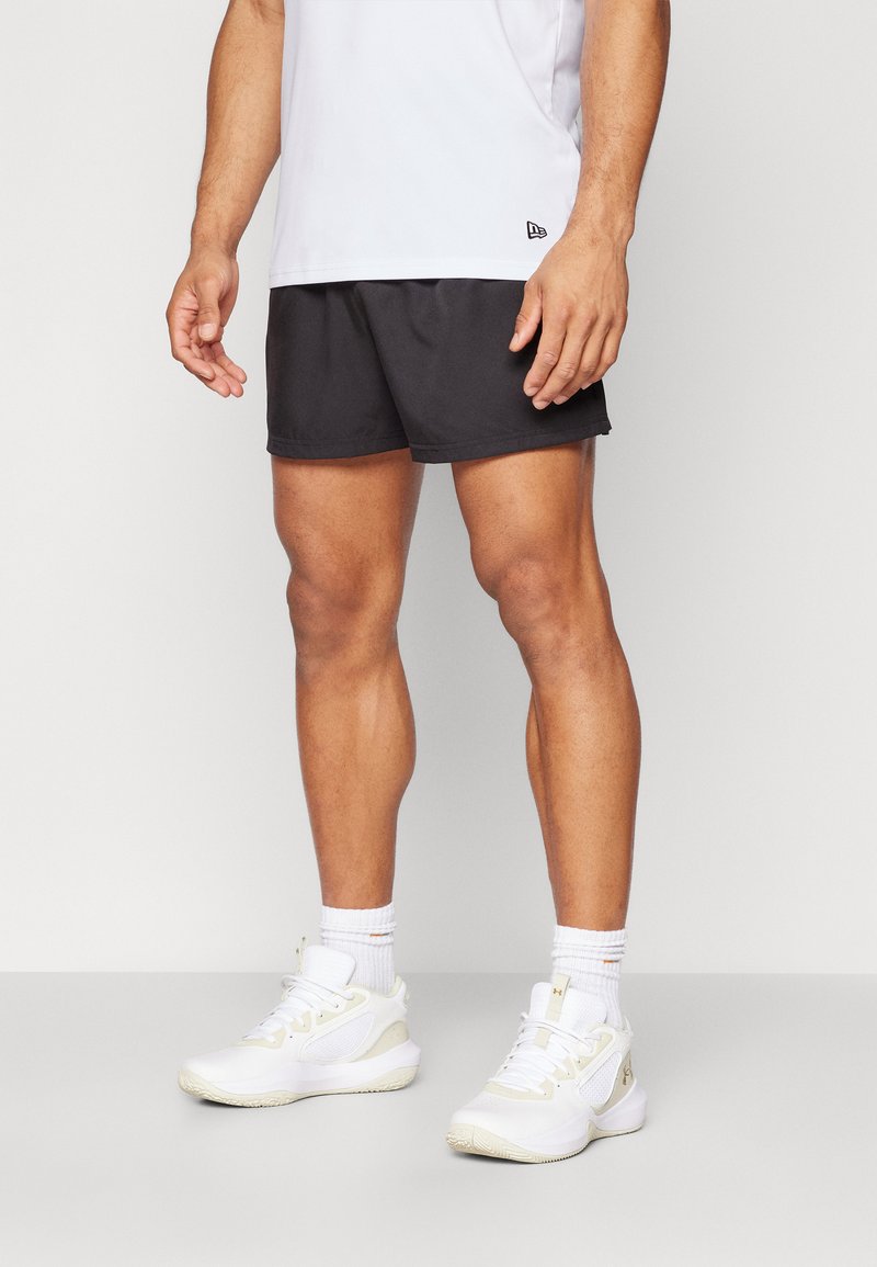 Pantalones cortos deportivos negros y una camiseta blanca de manga corta, combinados con zapatillas blancas y crema y calcetines blancos hasta el tobillo.