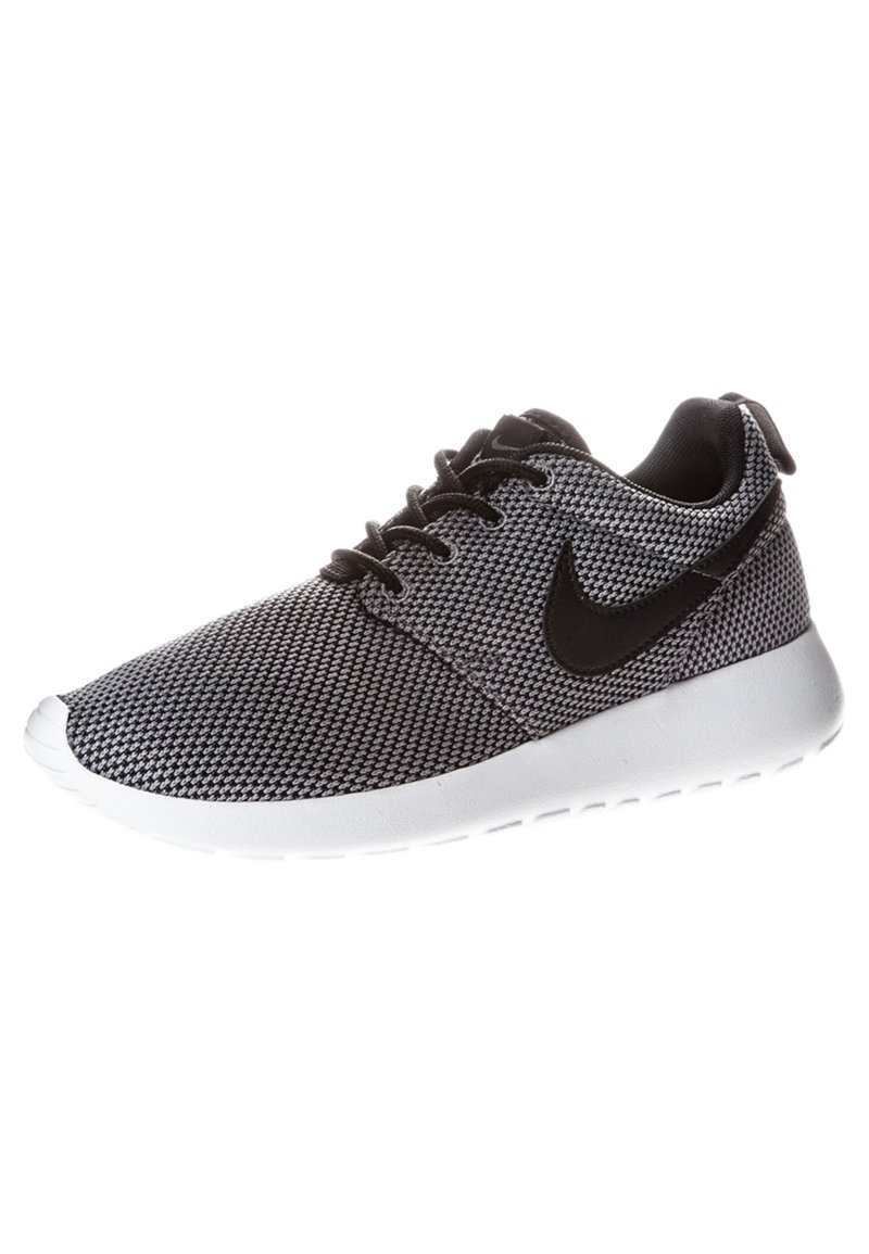 Black and white sneaker with a mesh upper, round toe, and a white rubber sole. Features black Nike logo and lace-up design.