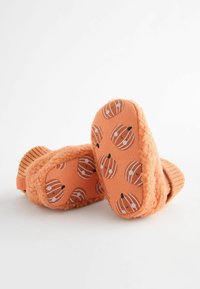 Orange fluffiga tofflor med pumpamönster på sulorna och ribbad mudd. Den mjuka texturen ger komfort och värme. Lämpliga för inomhusbruk.