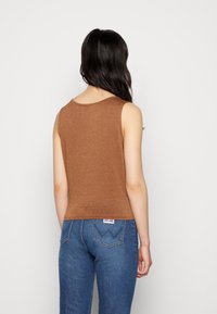 Bruin geribbelde tanktop met een ronde halslijn, met een aansluitend ontwerp. Gecombineerd met hoog gesneden blauwe denim jeans voorzien van een logo label.