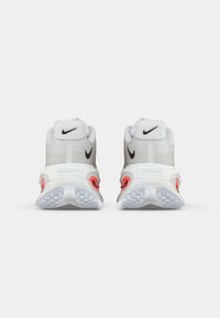 Λευκά αθλητικά παπούτσια με υφή στην πάνω πλευρά, μαύρο λογότυπο και ροζ λεπτομέρειες στη φτέρνα. Διαθέτουν διάφανο πάτο για καλύτερη πρόσφυση.