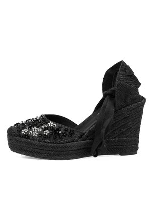 Sandalia espadrille negra con cuña, adornada con cuentas y lentejuelas, con lazo en el tobillo y tacón y suela trenzados y texturizados.