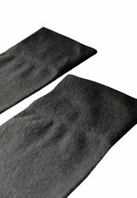 Svarta stickade benvärmare med en mjuk struktur och ribbade manschetter, med en sömlös design och en något sträckt utseende för komfort.