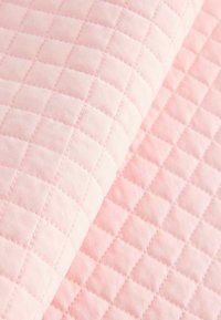 Light pink quilted fabric featuring a diamond pattern with a soft texture and visible stitching, creating a subtle three-dimensional effect.