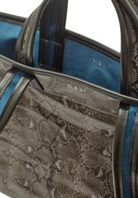 Stor handväska med en strukturerad grå ormskinnsmönstrad utsida, svarta läderdetaljer och en blå mockafoder. Har dubbla handtag och präglad logotyp.