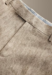 Pantaloni beige con trama a spina di pesce, passanti per cintura, vita con fascia e fodera della tasca visibile in tessuto a contrasto.