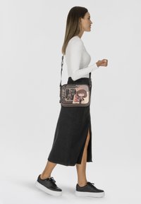 Borsa a tracolla con un design grafico che raffigura una ragazza e monumenti parigini, in morbidi toni di rosa e nero, con tracolla regolabile e chiusura a zip.