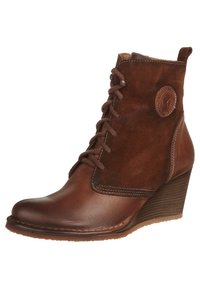 Botín de cuero marrón y ante hasta el tobillo con un tacón en cuña, punta redonda y cordones en el frente. Cuenta con un acento de logo circular en el costado.