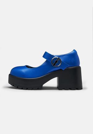 Chaussure style Mary Jane bleue avec talon plateforme noir épais et bride à boucle ronde, vue de profil sur fond blanc.
