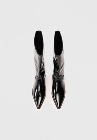 Sorte skinn ankle boots med spiss tå, strømlinjeformet design og blank overflate. Glidelås foran og tettsittende skaft for et strømlinjeformet utseende.