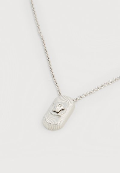 Ασημένιο κολιέ με αλυσίδα και ορθογώνιο μενταγιόν που φέρει ανάγλυφο κεφάλι λιονταριού και ακτινωτές υφασμάτινες γραμμές γύρω του.