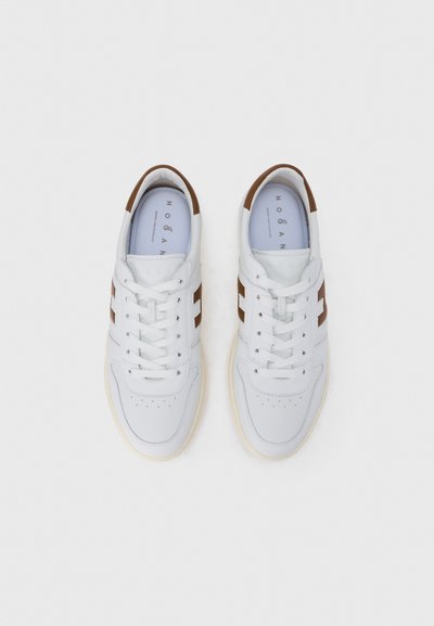 Λευκά δερμάτινα αθλητικά παπούτσια με καφέ λεπτομέρειες, σχέδιο με κορδόνια, στρογγυλεμένο μυτερό, υφασμένο επάνω μέρος και λογότυπο στην εσωτερική σόλα σε ανοιχτό μπλε χρώμα.